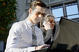 Young businessman typing in a laptop computer in urban background