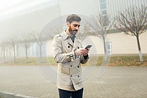 Young businessman typing text message on his way to work