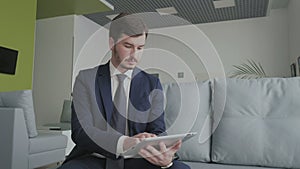 Young businessman uses a tablet in a vip lounge hall in the airport