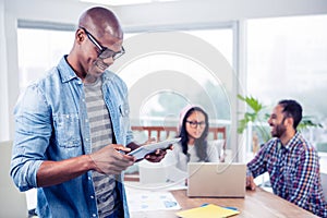 Young businessman using digital tablet while standing in office