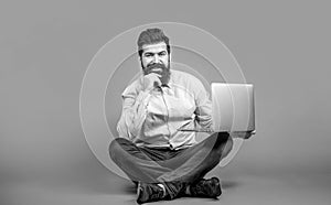 Young businessman using his laptop, pc. Happy young man sitting on the floor with and using laptop computer on