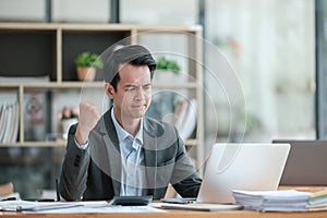 Young Businessman Using Laptop Computer in Modern Office. Manager Thinks About Successful Financial Ideas. Happy Man
