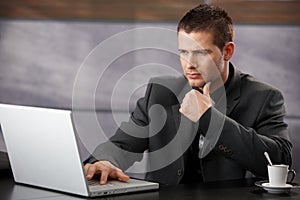 Young businessman using laptop in office