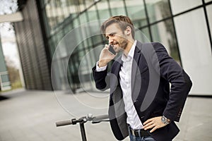 Young businessman using mobile phone  on electric scooter