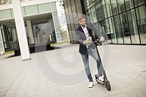 Young businessman using mobile phone on electric scooter