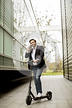 Young businessman using mobile phone  on electric scooter