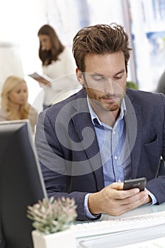 Young businessman using mobilephone at desk