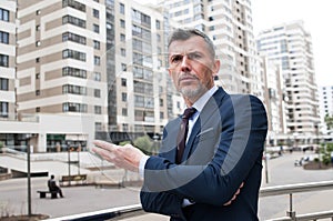 Young businessman using smartphone in the urban environment. The man in suit full length photo