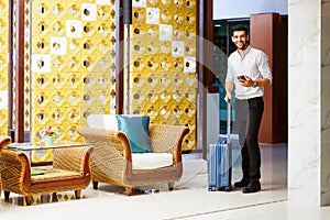 Young businessman walking with luggage in hotel corridor