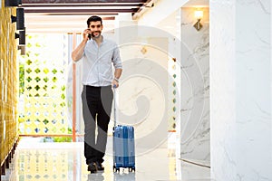 Young businessman walking with luggage in hotel corridor