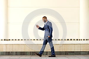 Young businessman walking outdoors and using cell phone