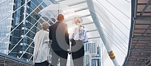 Young businessman walks with umbrella with business woman walking together while rains in economic district,concept of leader and