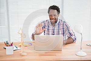 Young businessman waves at his laptop