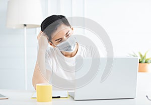 Young businessman wear mask and  working with laptop at home