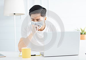 Young businessman wear mask and  working with laptop at home