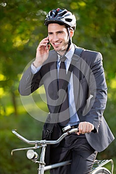 Young businessman wearing bike helmet and using mobile phone