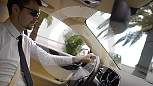 Young businessman wearing sunglasses driving cool car, beautiful view on city