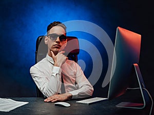 Young businessman in white shirt and sunglasses sitting at the workplace