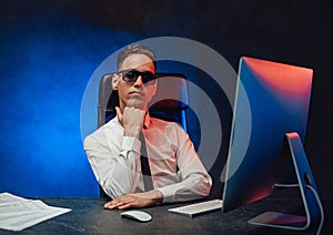 Young businessman in white shirt and sunglasses sitting at the workplace