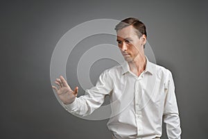 Young businessman in white shirt working with the invisible screen or virtual holographic interface.