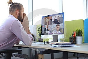 Young businessman working on computer, doing video conference with collegues on PC. Distance work. Coronavirus.