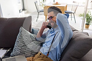 Young businessman working on laptop computer while sitting on sofa at home