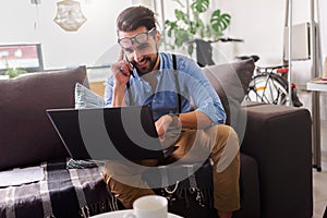 Young businessman working on laptop computer while sitting on sofa at home