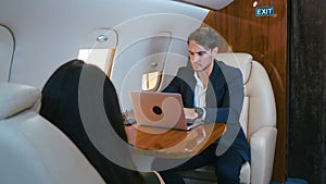 Young businessman working on laptop in his private plane. Successful business millionere man traveling in first class