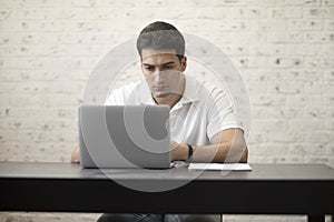 Young businessman working on laptop at home. Distant work and online education concept