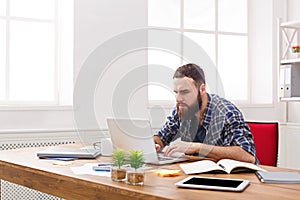 Young businessman working with laptop in modern white office