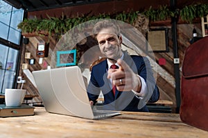 Young businessman working on laptop and pointing finger