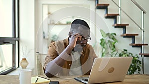 Young businessman working with laptop and sitting at table in home office.