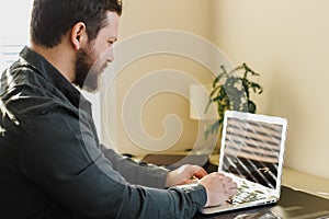 Young businessman working in office, looking at laptop computer screen.