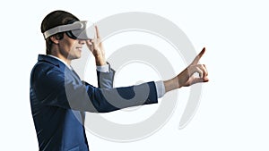 Young businessman working in virtual reality office in VR glasses, presses his finger virtual interface on abstract white backdrop