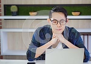 Young businessman is worried after looking at reports on the laptop screen. Anxiety causes stress concerns from work problems.