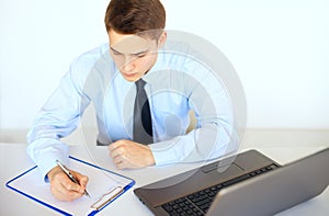 Young businessman writing on clipboard