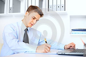 Young businessman writing on clipboard