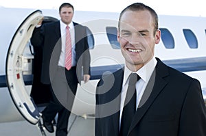 Young businessmen in front of corporate jet
