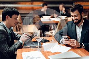 Young businessmen sit at a table in a restaurant.