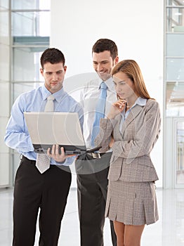 Young businesspeople looking at laptop screen