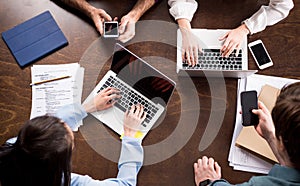 Young businesspeople sitting together at workplace and using digital devices