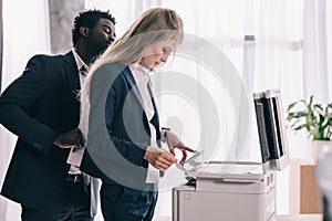 young businesspeople using copier together