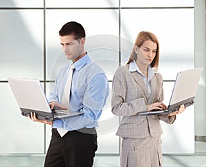 Young businesspeople using laptop in office lobby