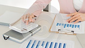 Young businesswoman analyzes cost graphs on desk in conference room with laptop