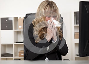 Young businesswoman blowing her nose