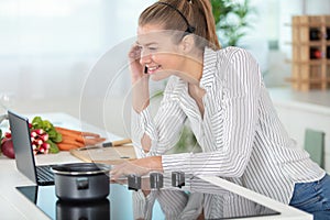 young businesswoman on conference call while cooking meal in kitchen