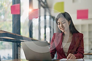 Young businesswoman creative team using post it notes in glass wall to writing strategy business plan to development