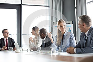 Young businesswoman discussing with male colleague in board room