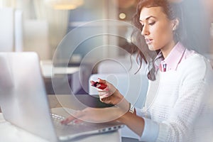 Mladý podnikateľka pitie káva a prenosný počítač počítač v kaviareň robiť pripojený robiť internetovej siete nakupovanie držanie úver karta 