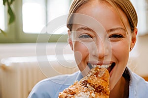 Young businesswoman eating croissant while having breakfast in cafe